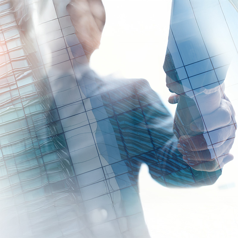 Due persone che si stringono la mano in segno di accordo o collaborazione, sovrapposte a un edificio moderno in vetro con riflessi, creando un effetto sovrapposto trasparente e professionale.